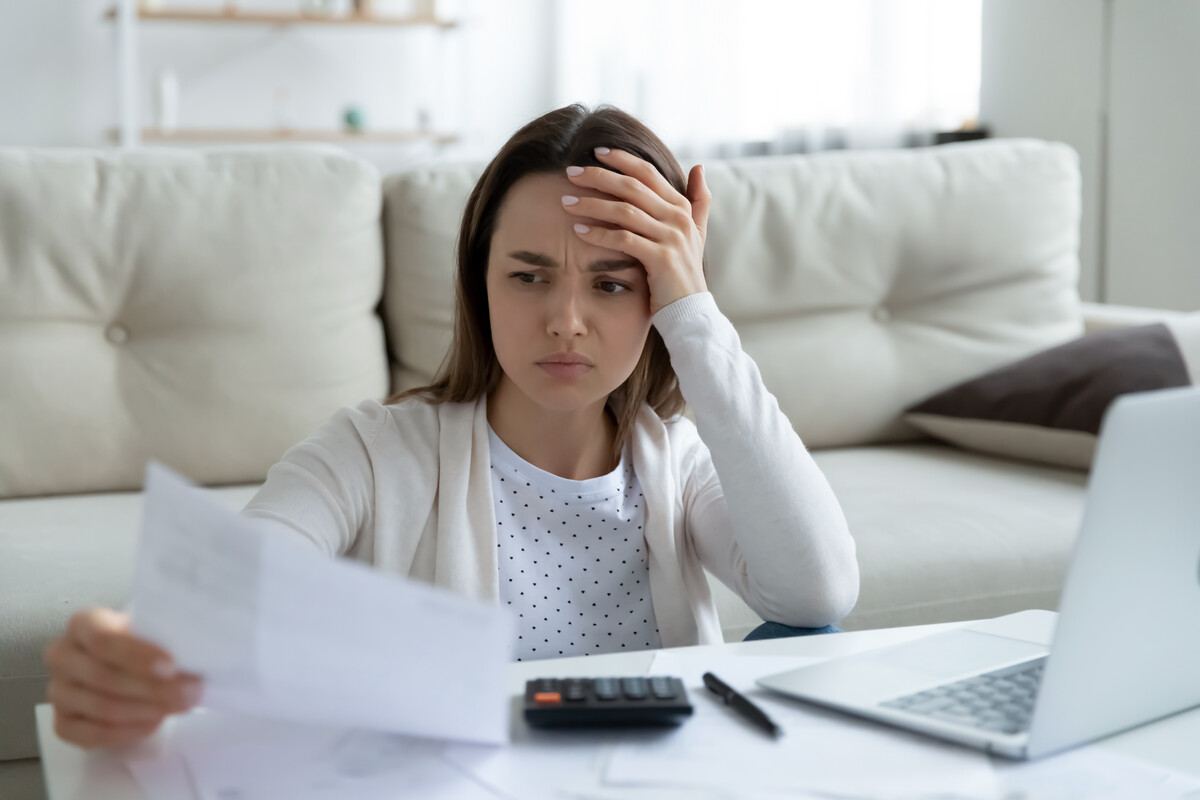 struggling business - stressed woman holding document letter with finance data feeling confused