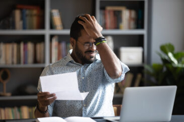 a male feeling frustrated staying at a desk struggling with his business